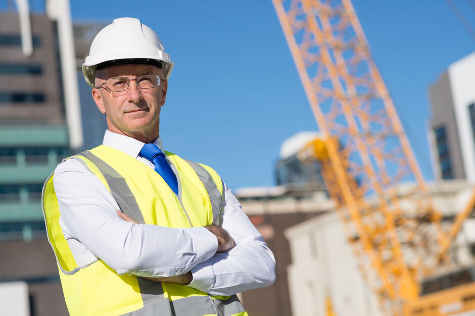 Construction site manager wearing white hard hat on a construction site.